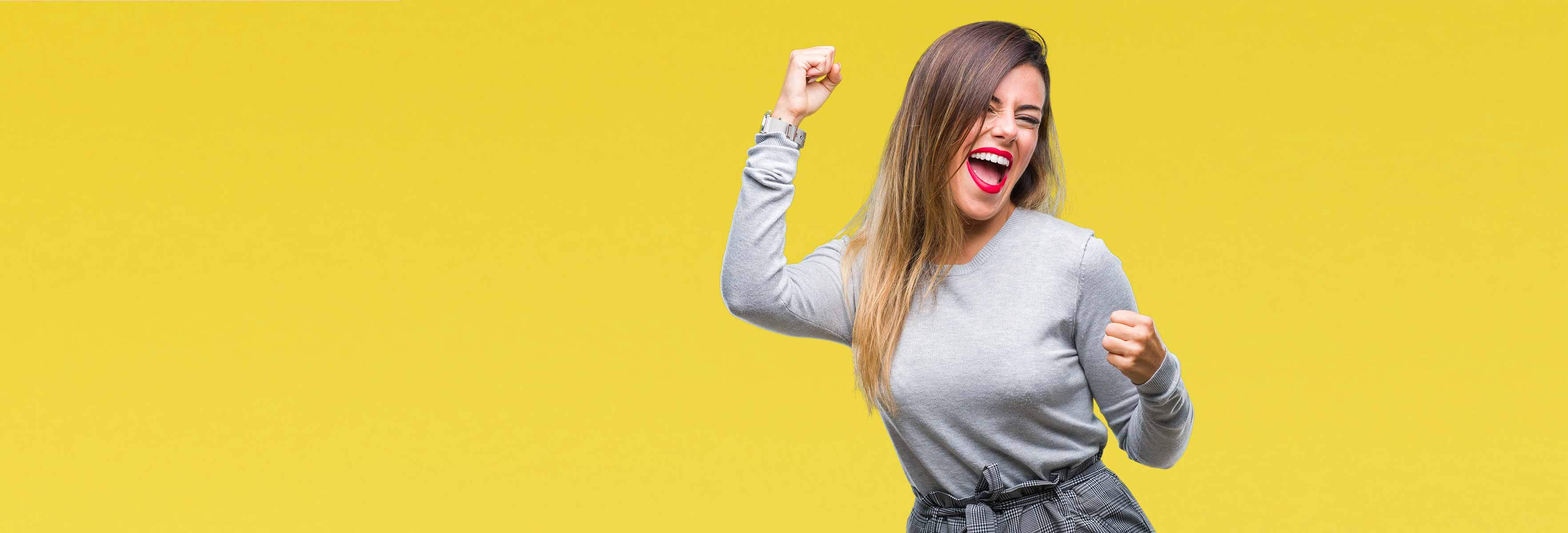 woman dancing and smiling in yellow background