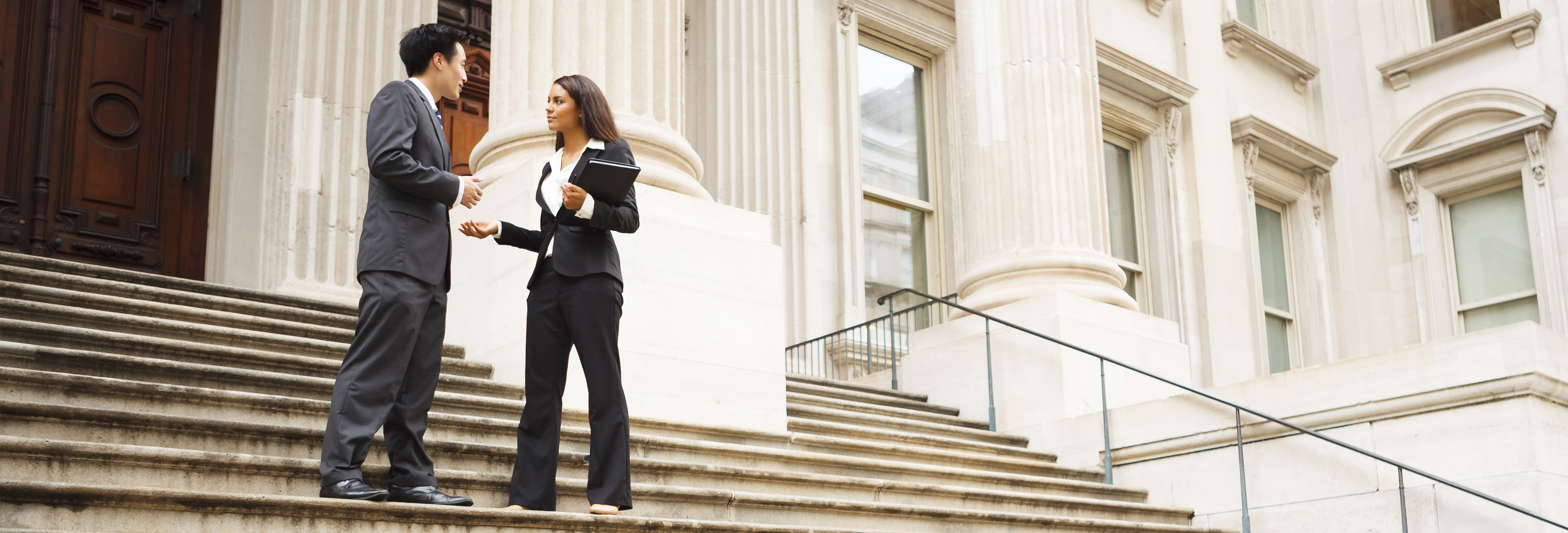 Smart dressed woman and man standing and talking on building stairs