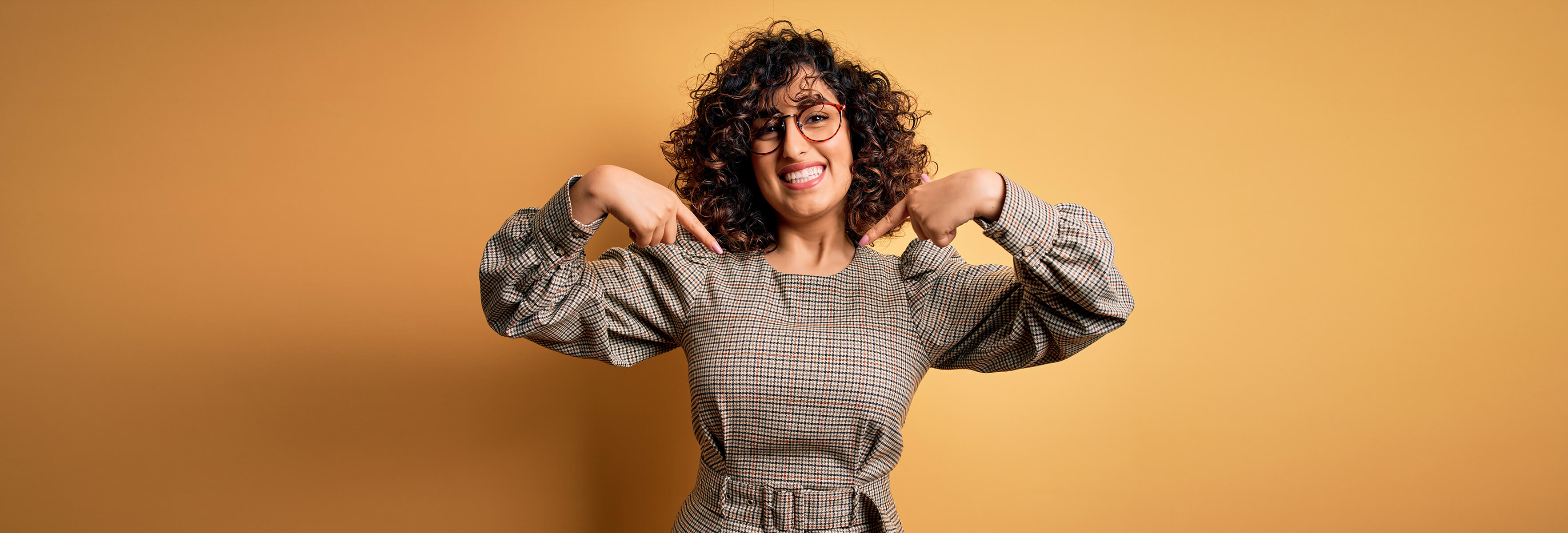 Smiling woman with glasses pointing down with both hands