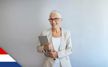 Smiling woman wearing glasses; holding closed laptop in both hands