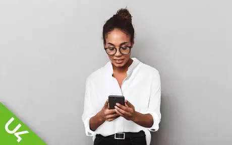 woman looking down at mobile phone held in both hands in front of her