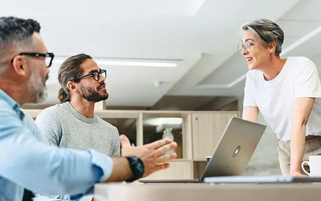 Three people in a modern office setting engaged in a discussion