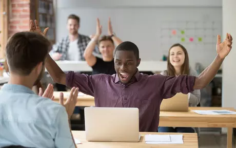 people working on laptops cheering 