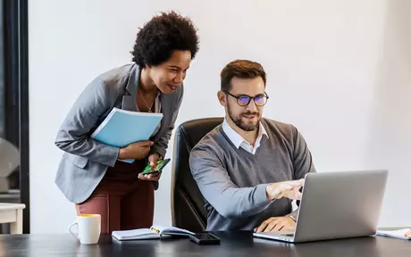 couple talking while pointing to a laptop