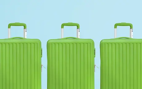 Three green hard-shell suitcases lined up against a light blue background