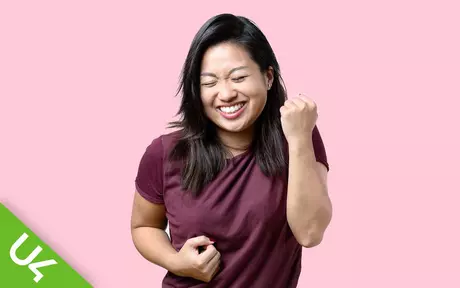 Woman smiling, with left hand half raised in celebration