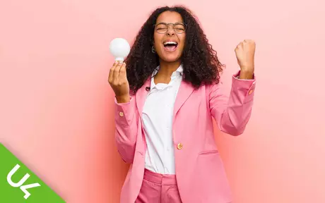 Woman shouting in celebration; holding lightbulb in one hand otehr hand clenched and half raised 