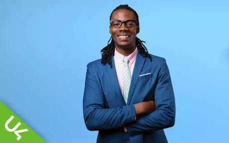 Man smiling/laughing, arms folded in front of him; on a lit blue background